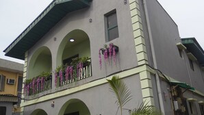 Um edifício de dois andares com varanda, janelas em arco e cestos com flores penduradas.