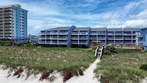 A beachfront hotel with multiple balconies, a pool area, and a sandy path leading to the entrance. - Best Ocean View in Carolina Beach.. (Carolina Beach)