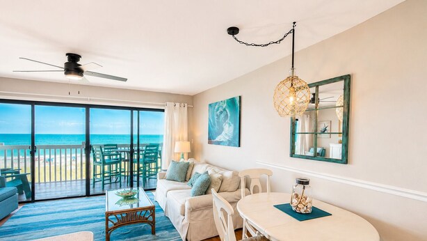 A room with a balcony, a ceiling fan, a dining table with chairs, and a view of the ocean. - Best Ocean View in Carolina Beach.. (Carolina Beach)