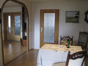 A dining area with a table set for two, a wooden door with frosted glass, and a painting on the wall. - Spacious vacation apartment with balcony (lake view), garden and direct lake access (Ascheberg)