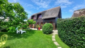 A house with a thatched roof, surrounded by a well-maintained lawn and a hedge.