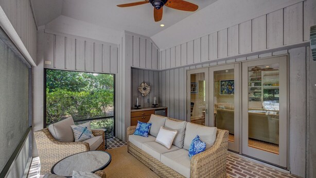 Un espace extérieur aménagé avec des meubles en osier, un ventilateur de plafond et une vue sur le paysage.