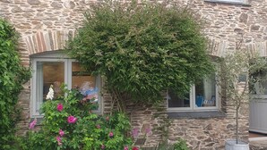 A stone house with two windows, a small garden with flowers, and a gravel driveway. - Courtyard cottage in Slapton, South Devon. 10 minutes drive to beach (Kingsbridge, Devon)