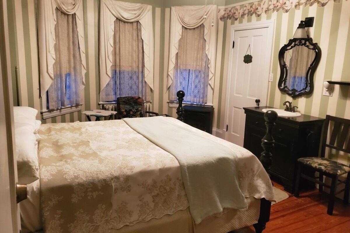 A bedroom with a large bed, a dresser, a chair, and a mirror.