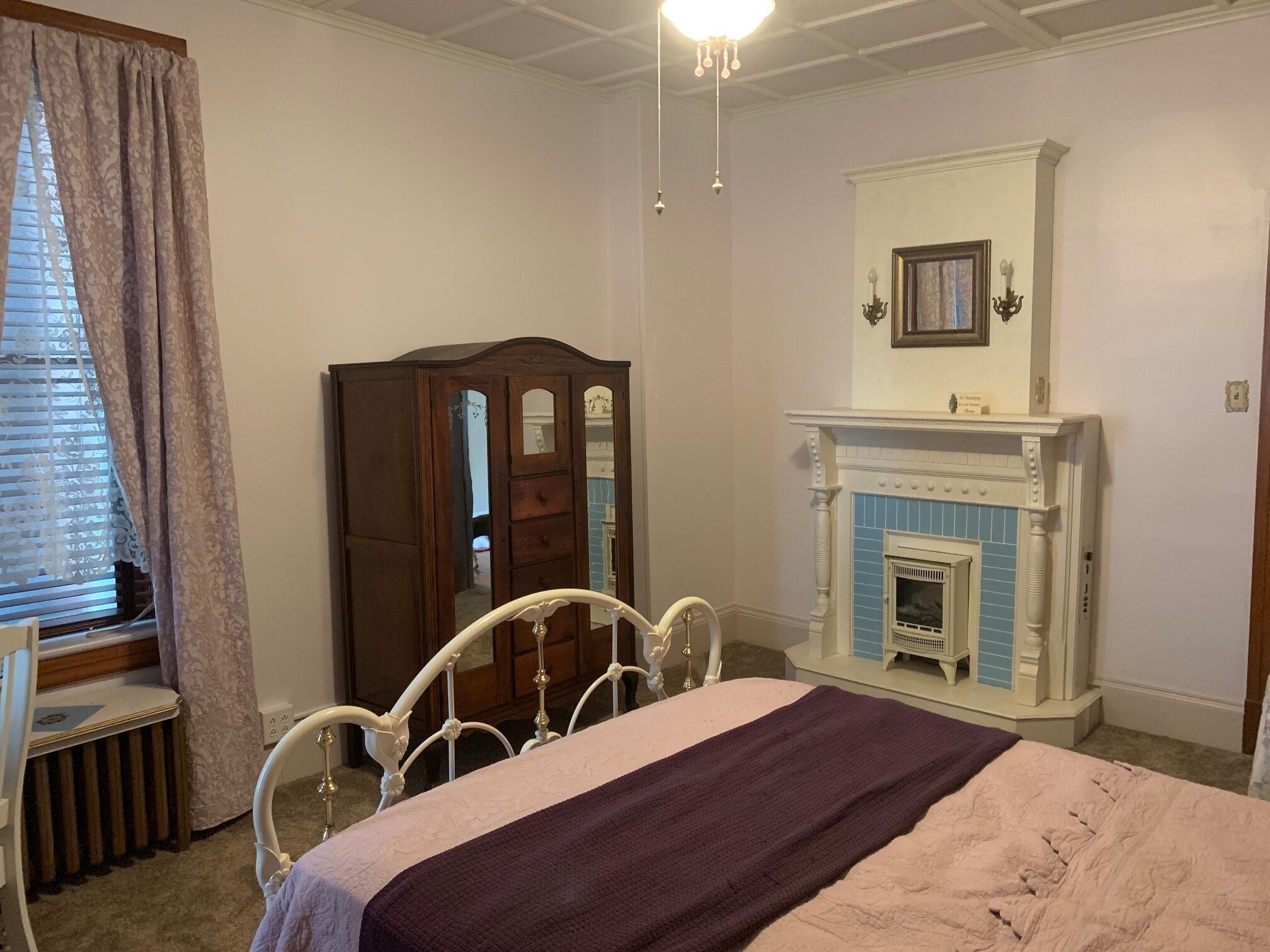 A bedroom with a bed, a dresser, a mirror, and a fireplace.