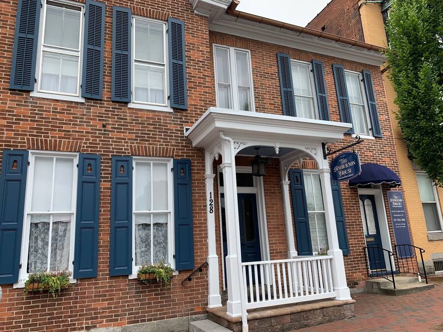 A brick building with blue shutters, a white porch, and a sign for The Anderson House.