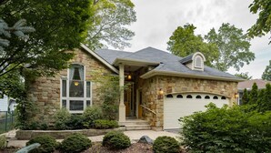 Une maison en pierre avec un garage, une véranda et un jardin bien entretenu.