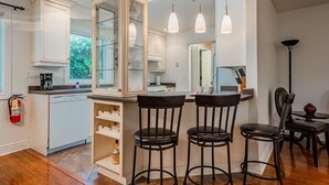 Une cuisine moderne dotée d’un îlot central, de tabourets de bar et de luminaires suspendus.