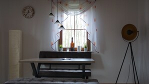 Un espace repas moderne avec une table en bois, un banc et des luminaires suspendus.