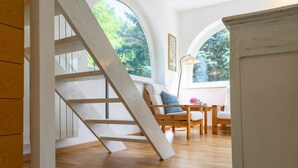 A wooden staircase leading to a loft bedroom with a view of trees through large arched windows. - Beautiful private villa for 6 guests with A/C, WIFI, TV, patio and panoramic view (Casalborgone)