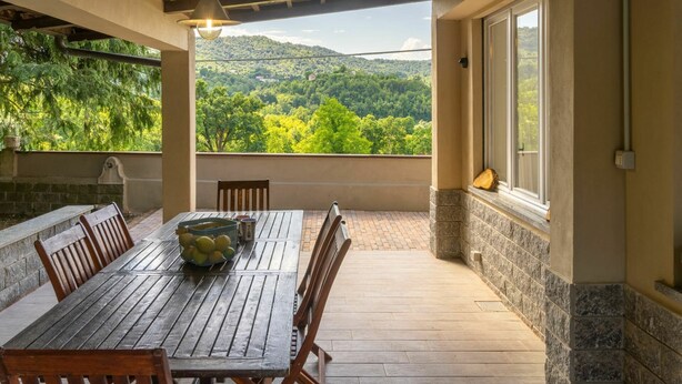 A covered patio with a wooden table and chairs, a bowl of lemons, and a view of a green landscape with hills. - Beautiful private villa for 6 guests with A/C, WIFI, TV, patio and panoramic view (Casalborgone)