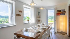 A dining area with a table set for six, large windows, and a view of the countryside. - Beautiful private villa for 6 guests with A/C, WIFI, TV, patio and panoramic view (Casalborgone)