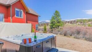 A hot tub with steps, a red house, and a view of a residential area with mountains in the background.