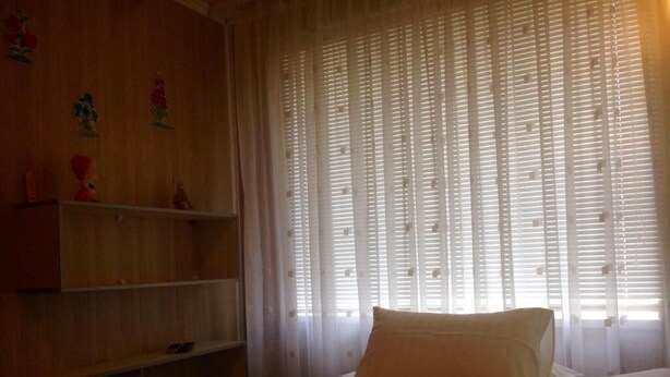 Un dormitorio con cama, estante y ventana con persianas.