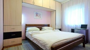 Una habitación de hotel con cama, escritorio con computadora y armario.