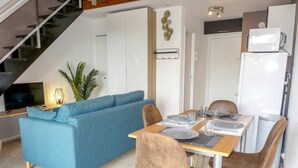 A modern living space with a blue sofa, dining table with chairs, and a staircase. - Beautiful apartment for 4 people with pool, WIFI, A/C, TV and terrace (Fréjus)