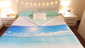 A bed with a sky and sea print, two pillows, a bedside table with a lamp, and a sign saying "LOVE". - Wide Apartment with Terrace in City Center (Napoli)