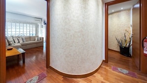 Un intérieur moderne avec un mur incurvé, un plancher en bois, un canapé et une plante en pot.