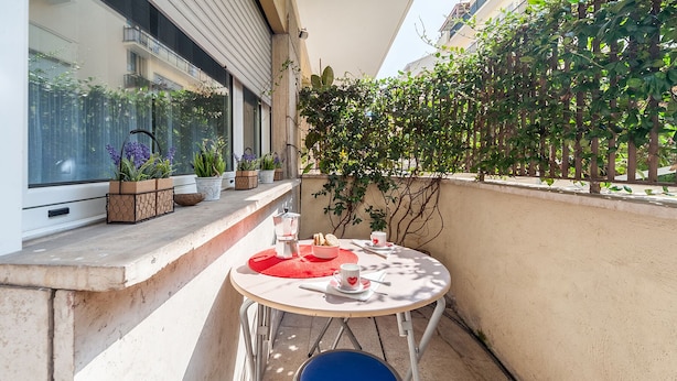 Un petit balcon avec une table ronde, une chaise bleue et des plantes en pot.