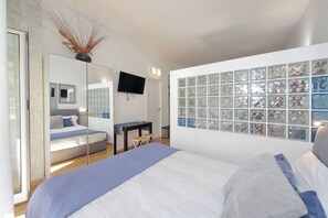 A modern bedroom with a large bed, a TV mounted on the wall, and a window with decorative glass panels. - St. Peter3 - Loft with terrace (Roma)