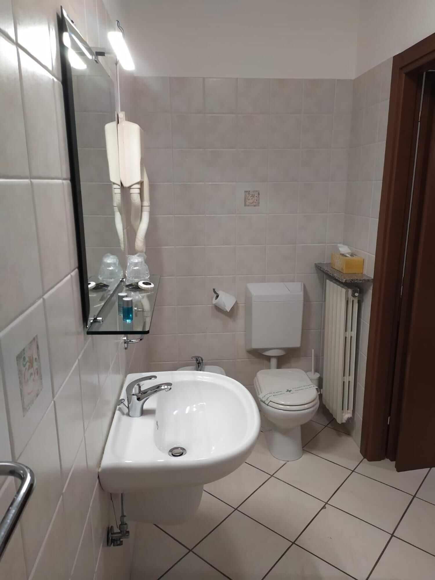 A bathroom with a white sink, toilet, and mirror.