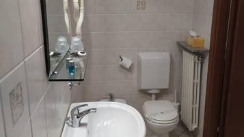A bathroom with a white sink, toilet, and mirror.