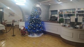 Un hall d’hôtel décoré d’un sapin de Noël, avec un comptoir d’accueil et un espace bar.