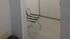 Une pièce avec une armoire blanche, un banc en métal et un luminaire au plafond.