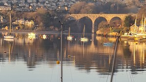 A harbor with boats, a bridge, and residential buildings in the background. - Riverside retreat by Brunel’s Bridge, balcony view, off‑road parking, EV charger (Plymouth)