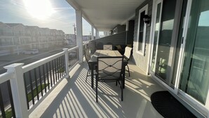 A balcony with a table and chairs, overlooking a residential street.