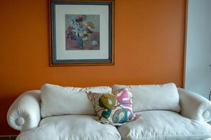 A white sofa with a colorful pillow and a framed painting on the wall. - 3 rooms apartment in Palermo area. (Palermo)