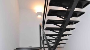 A modern staircase with a black metal design and a skylight at the top.