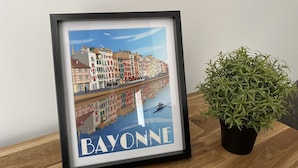 A framed picture of a colorful town with the word "BAYONNE" at the bottom.