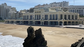 A coastal building with multiple stories, large windows, and a balcony.