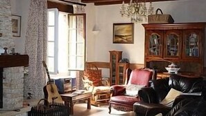 A traditional living room with a fireplace, a chandelier, and a wooden cabinet.