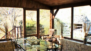 A glass-top table with chairs in a stone-walled room with large windows.