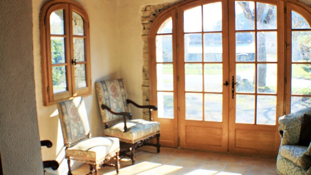 A room with a stone wall, wooden door, and two upholstered chairs.