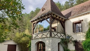 A traditional building with a stone base and a wooden upper structure, featuring a prominent arched window and a small tower-like section.