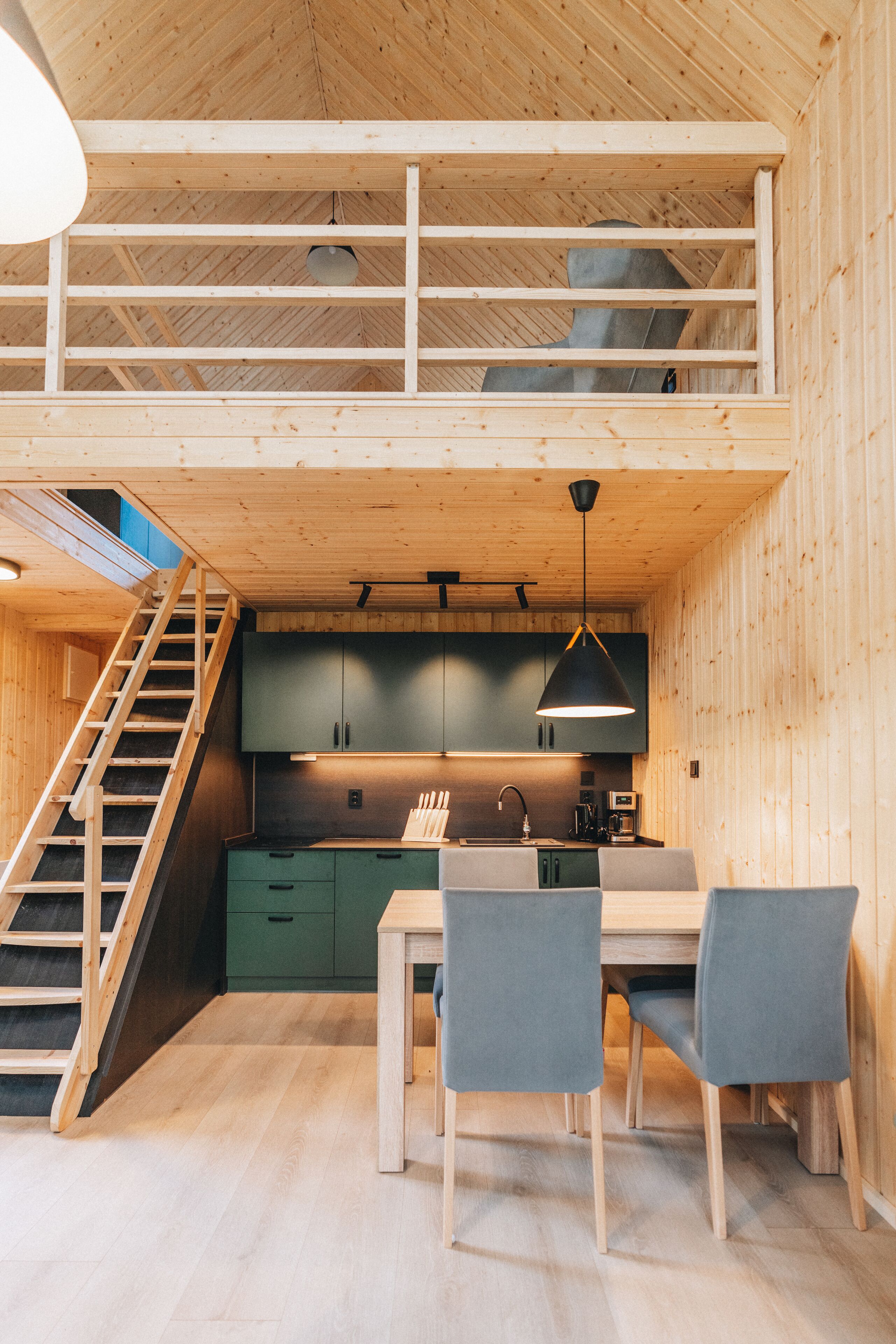 Un interior de madera con cocina, comedor y una escalera.