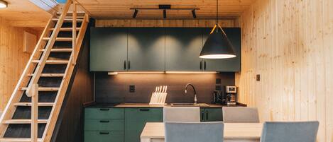 Un interior de madera con cocina, comedor y una escalera.