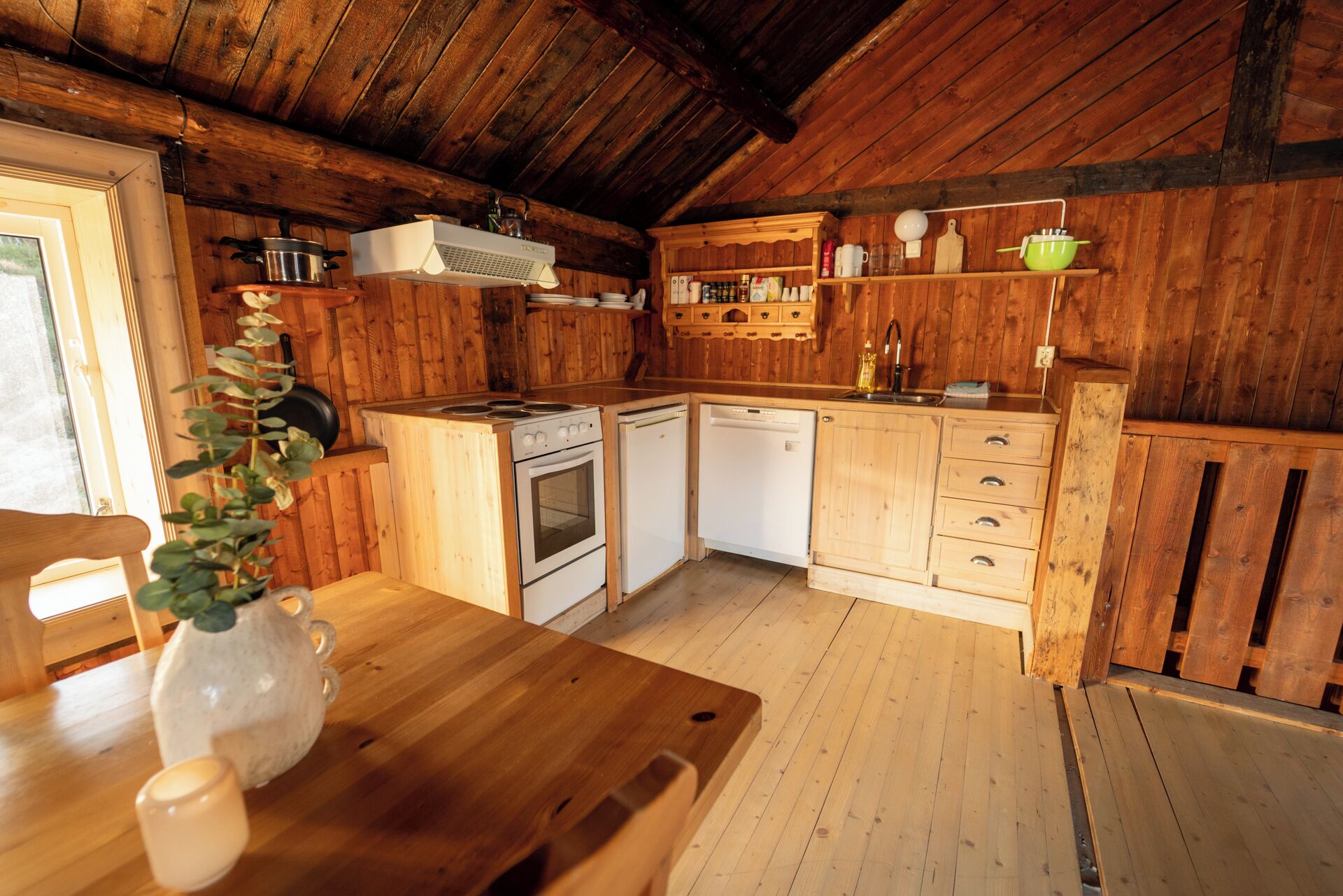 A compact kitchen with wooden cabinets, a stove, a dishwasher, and a sink.
