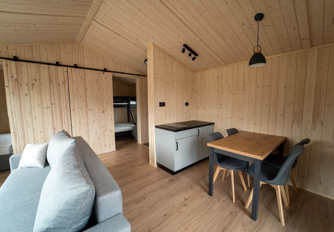 Un intérieur moderne avec un plafond en bois, un canapé, une table à manger avec des chaises et un coin cuisine.