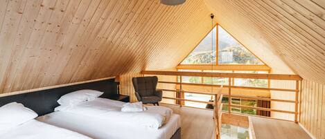 A wooden interior with a bed, a chair, and a window.