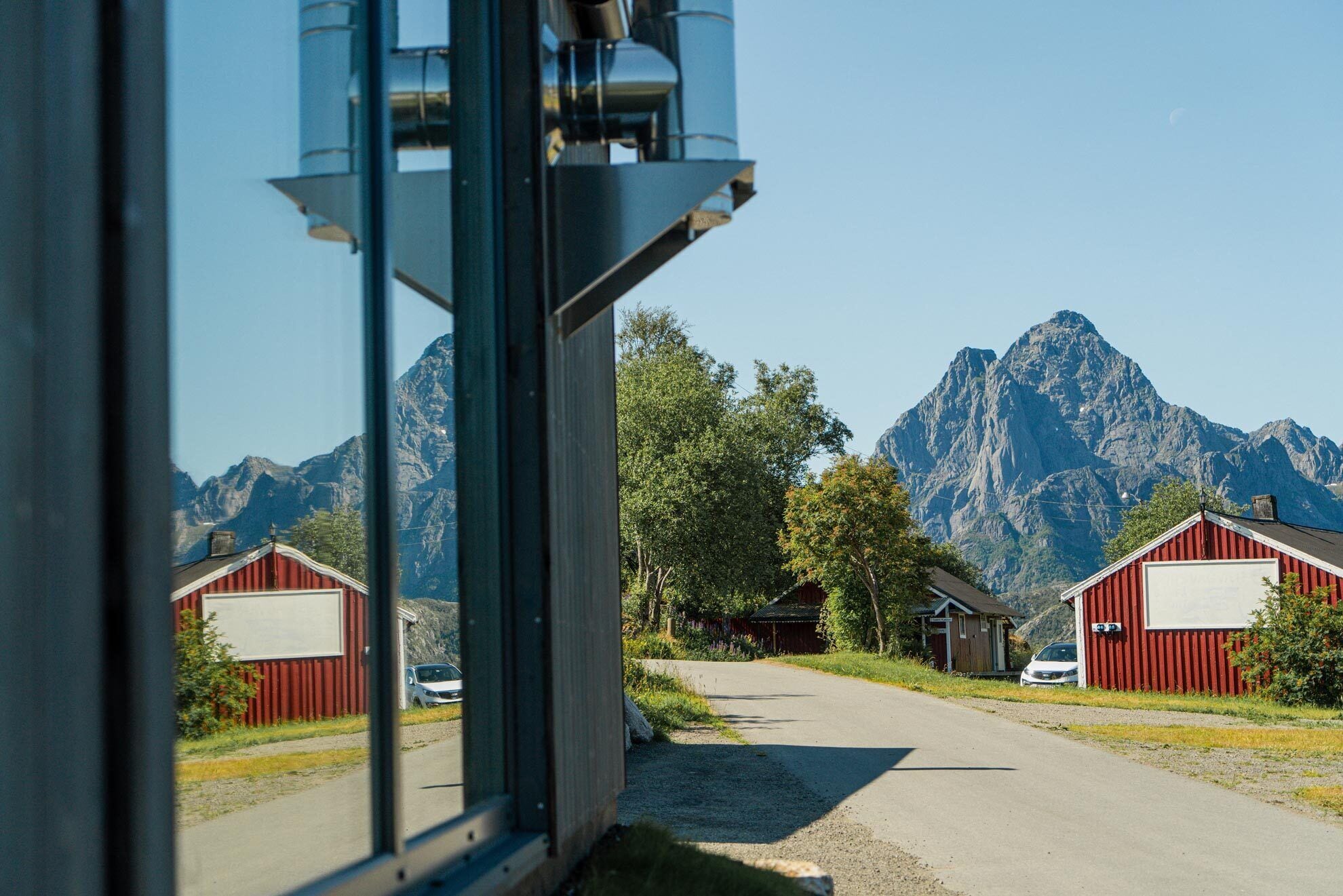 A view through a window of a building with red barns and a mountain in the background.