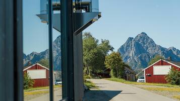A view through a window of a building with red barns and a mountain in the background.