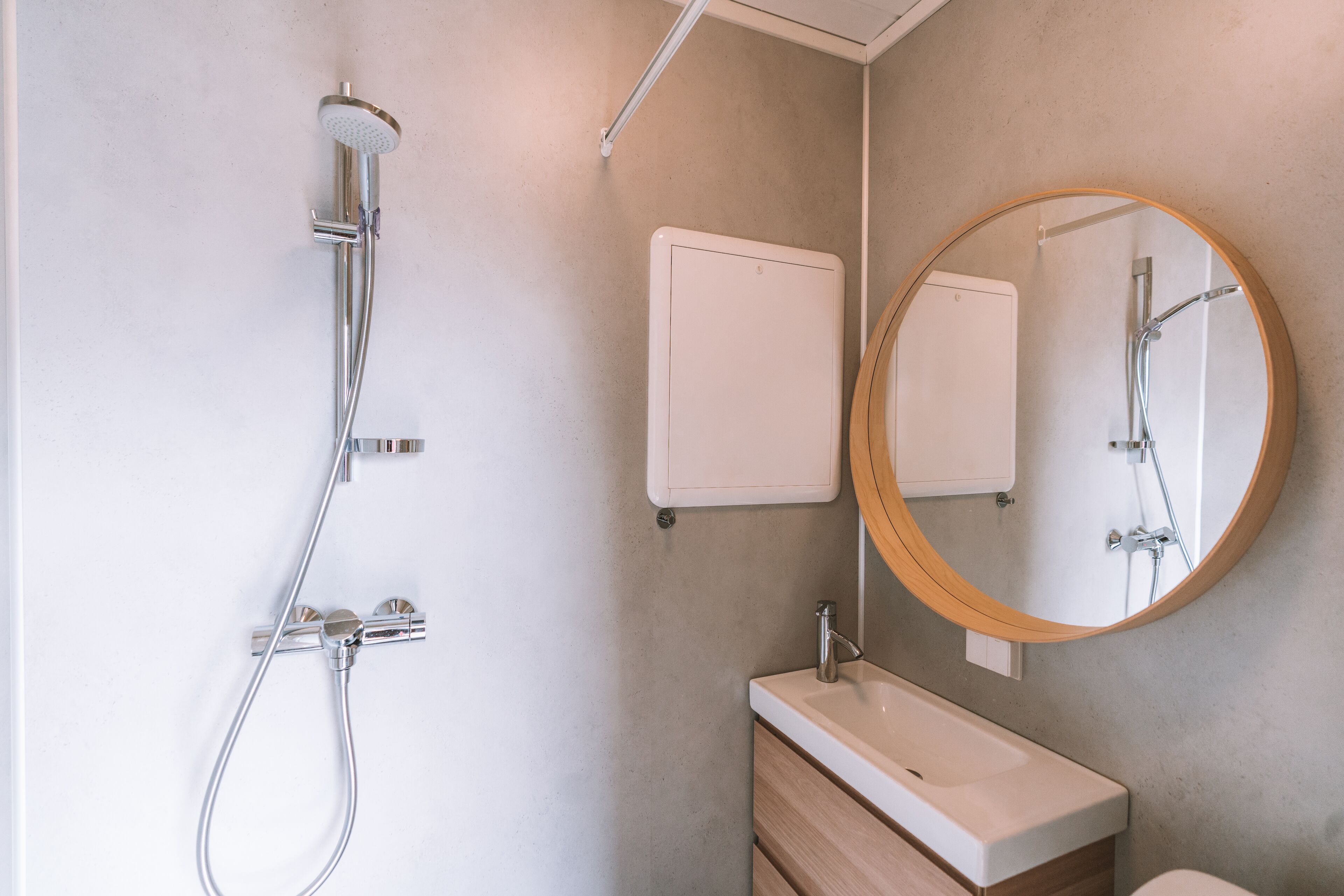 Un baño moderno con ducha, lavamanos y espejo.