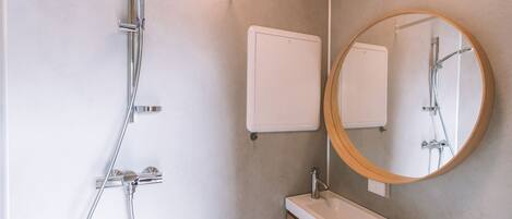 Un baño moderno con ducha, lavamanos y espejo.