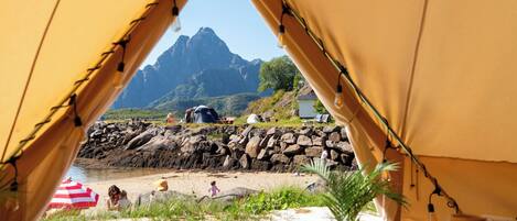 A tented area with a view of a mountainous landscape and a beach.