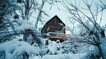 A cabin with a balcony, surrounded by snow-covered trees.