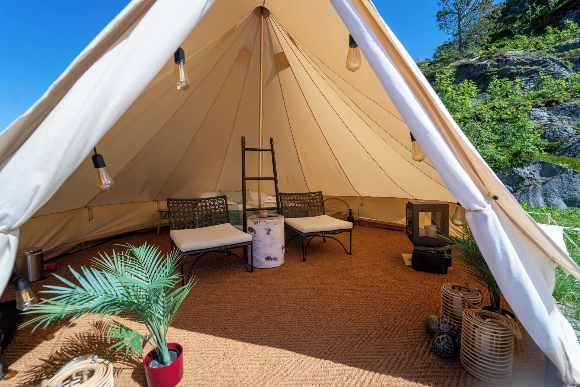 A tent with two chairs, a table, and a ladder.